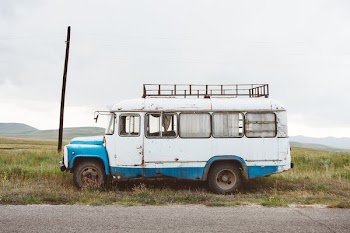 white and blue vehicle near black post under white clouds at daytime