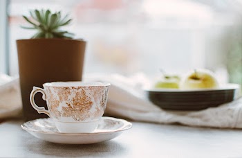 White and Brown Floral Ceramic Teacup on White Ceramic Saucer Near Brown Pot