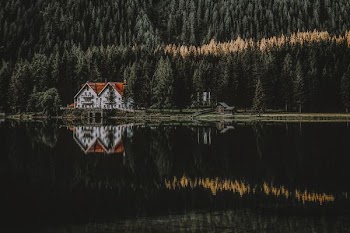 white and brown house with reflection on water surrounded with trees