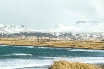 white and brown mountains beside body of water