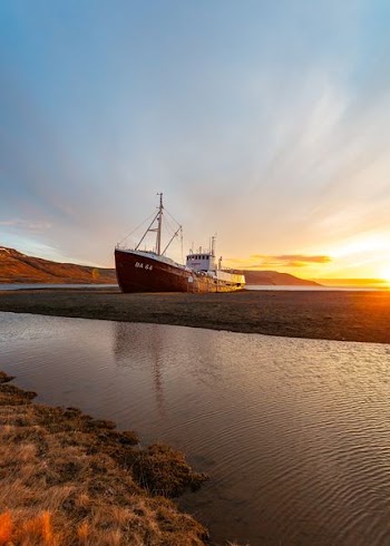 white and brown ship on seashore under sunrise