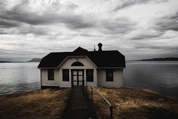White and Brown Wooden House Near Calm Body of Water Under Cumulus Clouds