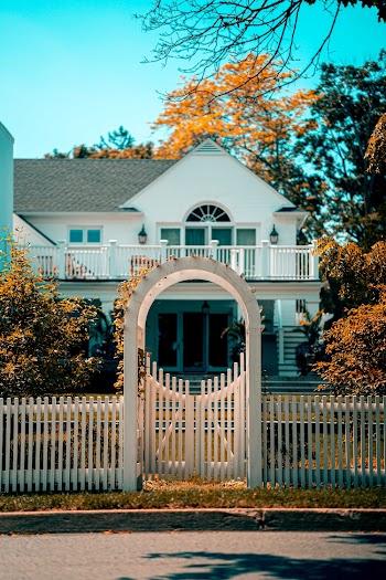 White and Gray 2-storey House Behind White Gate Panel