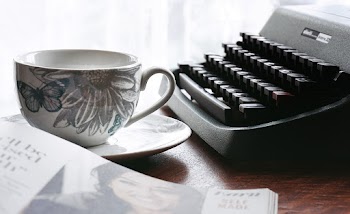 White and Gray Floral Ceramic Cup and Saucer Near Black Typewriter and Book
