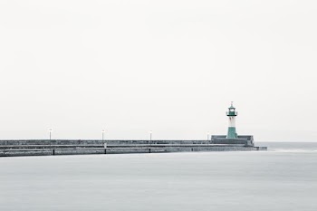 white and green lighthouse near body of water