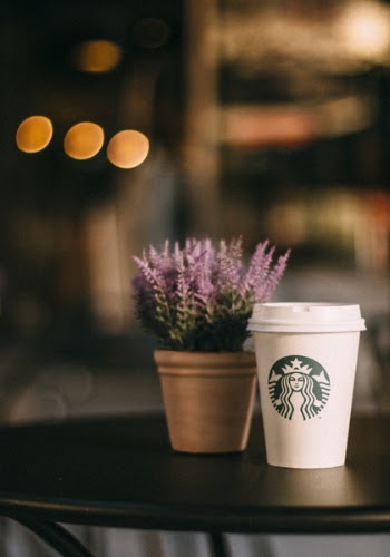 White and Green Starbucks Tumbler Beside Lavender Flowers on Table