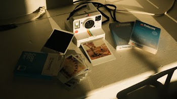 White and Multicolored Polaroid Instant Camera With Pictures