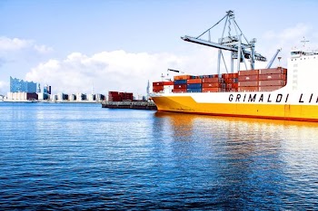white and orange cargo ship with metal lifting equipment