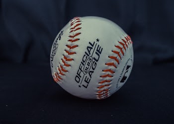 White and Orange Official League Baseball on Black Textile