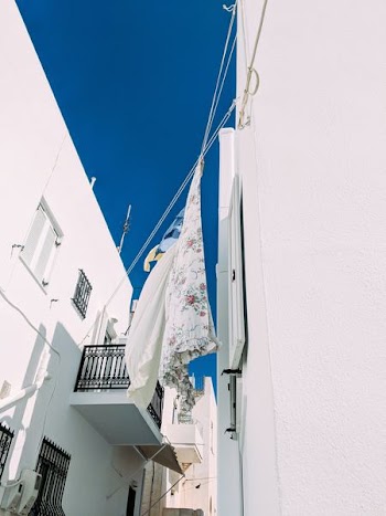 white and pink floral textile hanged in between concrete buildings