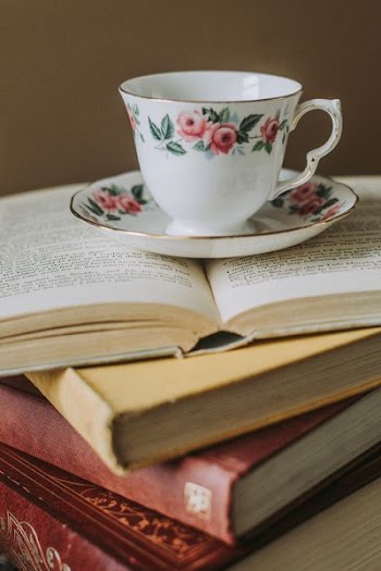 white-and-pink teacup on top of opened book