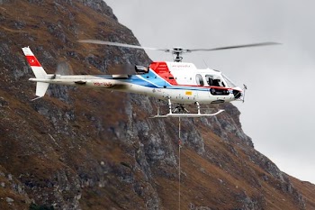 white and red helicopter flying near mountain terrain during daytime
