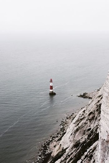 white and red lighthouse beside body of water