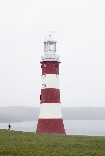 White and Red Lighthouse Surrounded by Green Grass Field