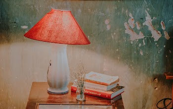 White and Red Table Lamp, Assorted-color Books, and White Petaled Flower in Clear Glass Vase on Brown Wooden End Table