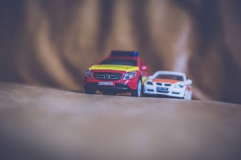 White Beside Red Toy Car on Brown Leather