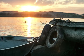 White Boat on Dock Near Two Auto Tires during Sunset