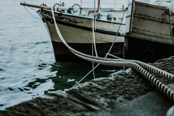 White Boat on Harbor With Brown Rope Through Concrete Pavement