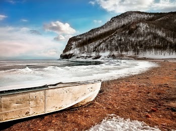 White Boat on Seashore Near Mountain Under White and Blue Sky
