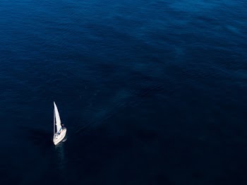 White Boat Sailing On Body Of Water