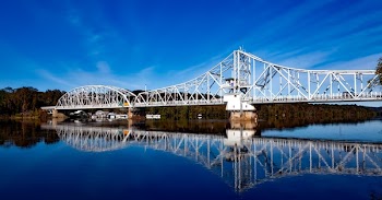 White Bridge Above Body of Water Creating a Reflection Under White Clouds