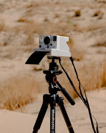 White Camera on Black Tripod