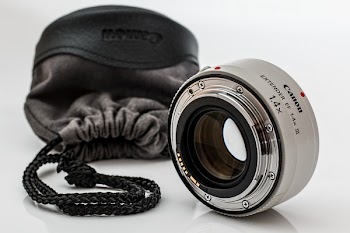 White Canon Camera Lens With Black Bag on White Surface