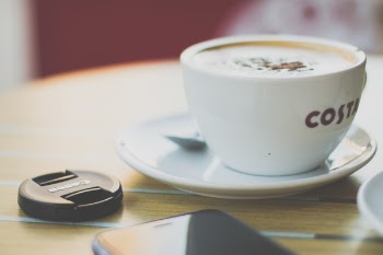 White Ceramic Cup Beside Black Smartphone