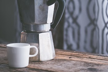 White Ceramic Cup Beside Stainless Steel Kettle on Brown Wooden Table