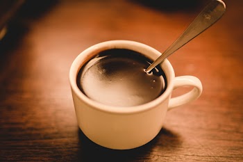 White Ceramic Espresso Cup Filled With Coffee On Brown Wooden Surface