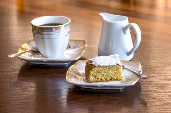 White Ceramic Mug Filled With Black Liquid Beside Baked Bread on Ceramic Saucer