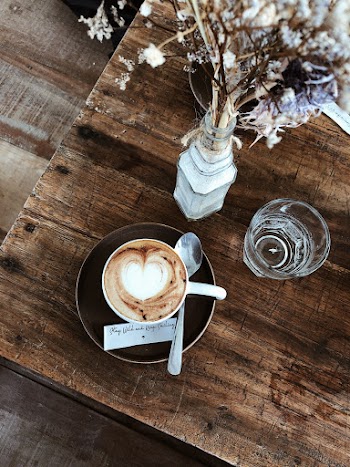 White Ceramic Mug on Black Saucer Next to Glass of Water
