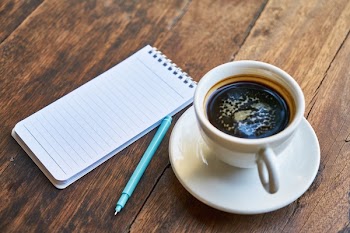 White Ceramic Teacup Beside White Ruled Paper