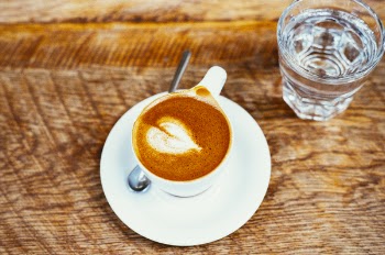 White Ceramic Teacup on White Ceramic Saucer Filled With Brown Coffee Beside Clear Glass Cup Filled With Water
