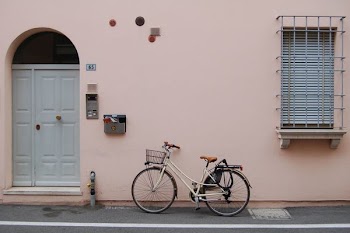 white commuter bike parked on pink painted wall building