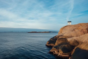 white concrete house on rock formation near sea at daytime
