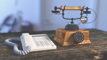 White Electric Home Phone Close to Rotary Phone on Table