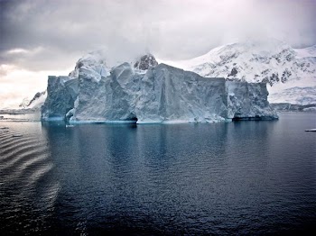 white iceberg near white mountains