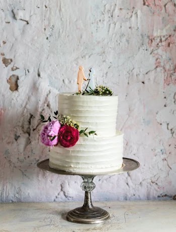 white icing-covered wedding cake on gray cake tray