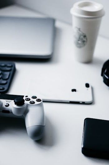 white iPhone 7 Plus next to white Sony PS4 DualShock 4 and gray laptop computer on table