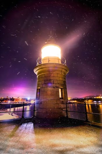 white lighthouse near cityscape