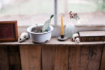 White Metal Bowl Beside Yellow Wax Candle on Brown Wall