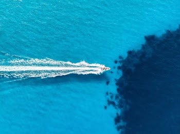 white motor boat on body of water during daytime