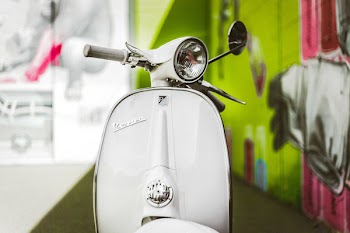 White Motor Scooter Parked Near Green and Pink Wall