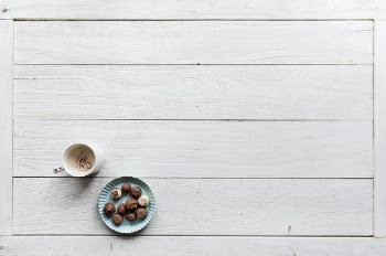 White Mug Filled With Coffee Beside Baked Pastries on Paper Plate All on Top of White Wood Surface