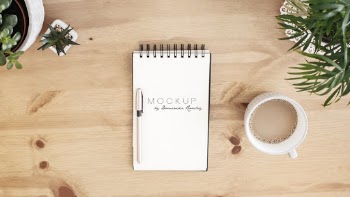 White Notebook Beside Coffee Cup
