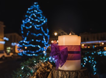 White Pillar Candle on the Log in a Distance of Blue Led Light Christmas Tree
