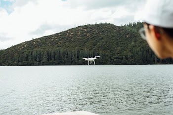white quadcopter drone near body of water
