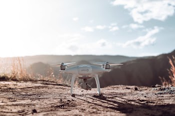 White Quadcopter Drone on Top of Brown Soil