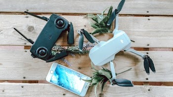 White Quadcopter Drone With Controller on Wooden Surface